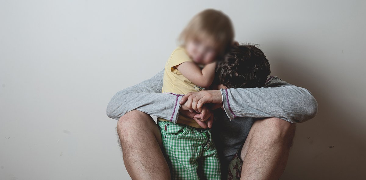 Alkoholisierter Vater, der ein kleines saueres Kind umarmt