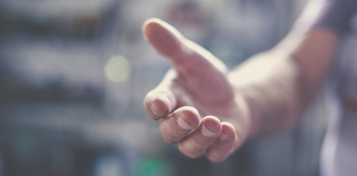 Eine ausgestreckte Hand eines Mannes, der Hintergrund ist verschwommen dargestellt